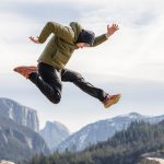 Dynamic action shot of a man jumping over rocks with Yosemite's distinctive mountains in the background.