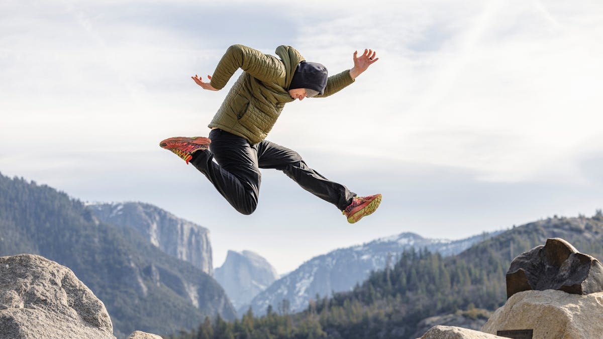 Dynamic action shot of a man jumping over rocks with Yosemite's distinctive mountains in the background.